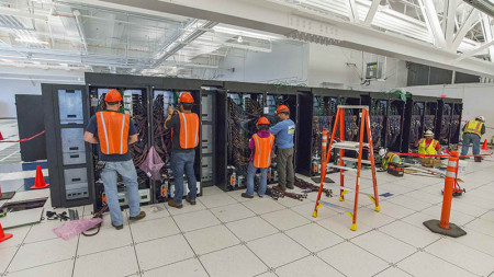 Technical workers in safety gear install the Cori Supercomputer racks and cables at NERSC.