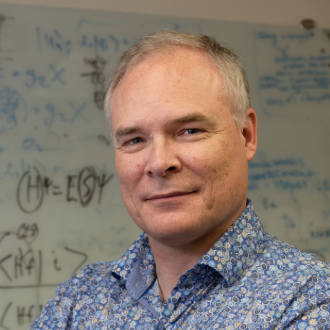 Bert de Jong wearing a blue patterned shirt in front of a white board.