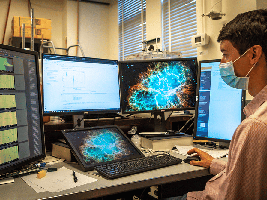 An AQT reseracher investigates data using four computer screens