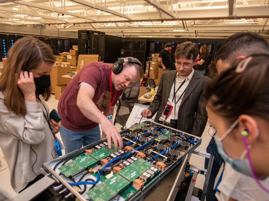 NERSC machine room tour where attendees examine a blade from a supercomputer with a guide.