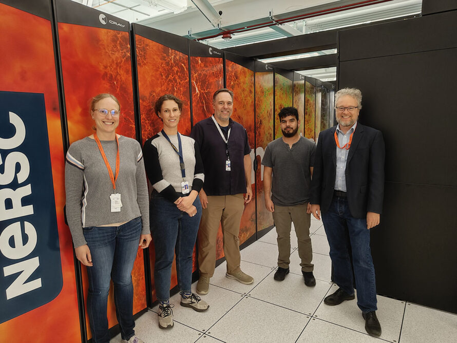 Members of NERSC and ESnet pose in front of the Perlmutter supercomputer cabinets