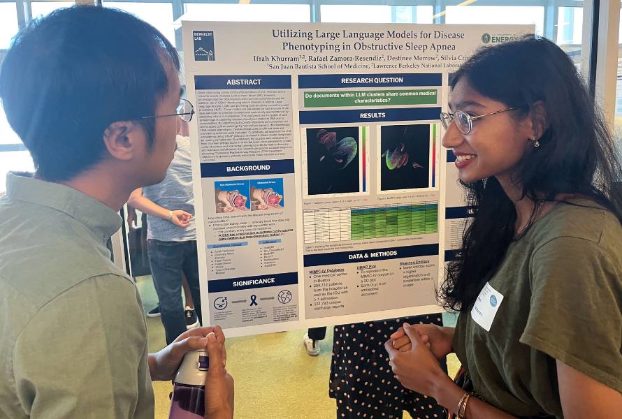 Summer student Ifrah Kurram explains her poster to a fellow participant.