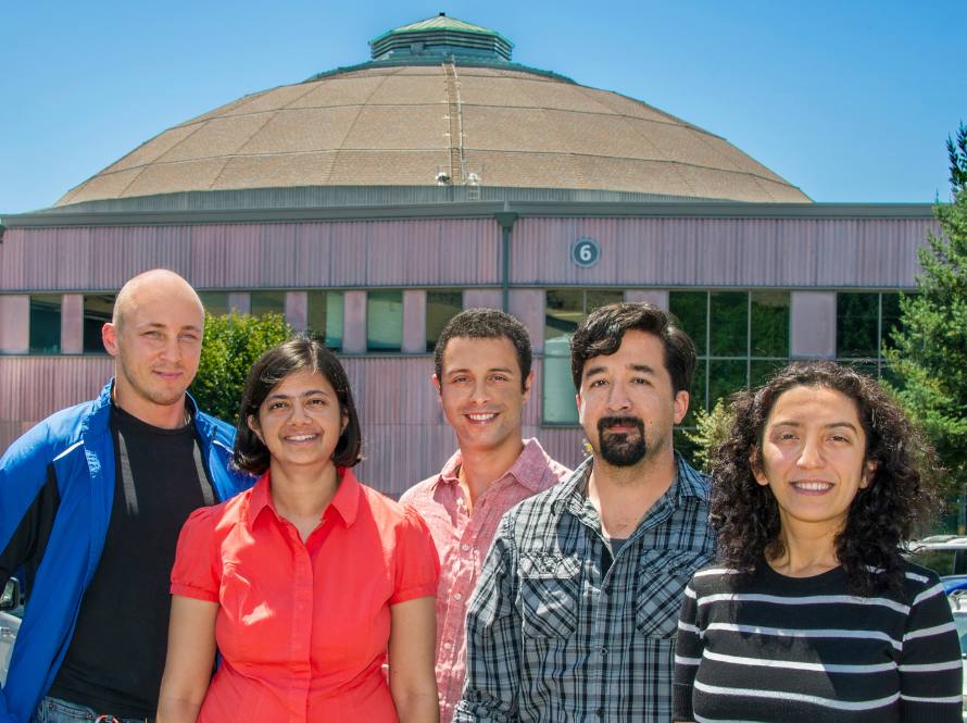 Five former Alvarez fellows, three men and two women, post in front of the Advanced Light Source buiding at Berkeley Lab.