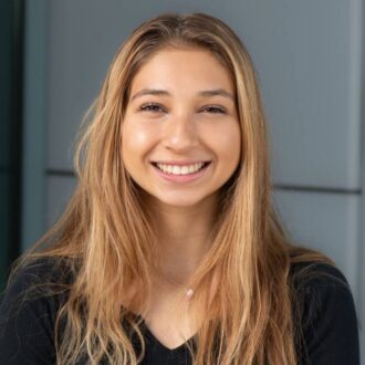 Headshot of Iliana Marrujo, a woman with medium complexion, long golden brown hair, wearing a black blouse.