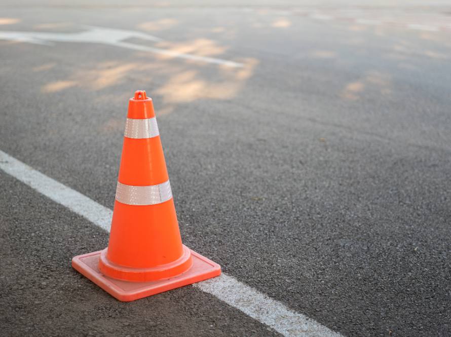 Photo of an orange traffic cone deployed on the side of a roadway.