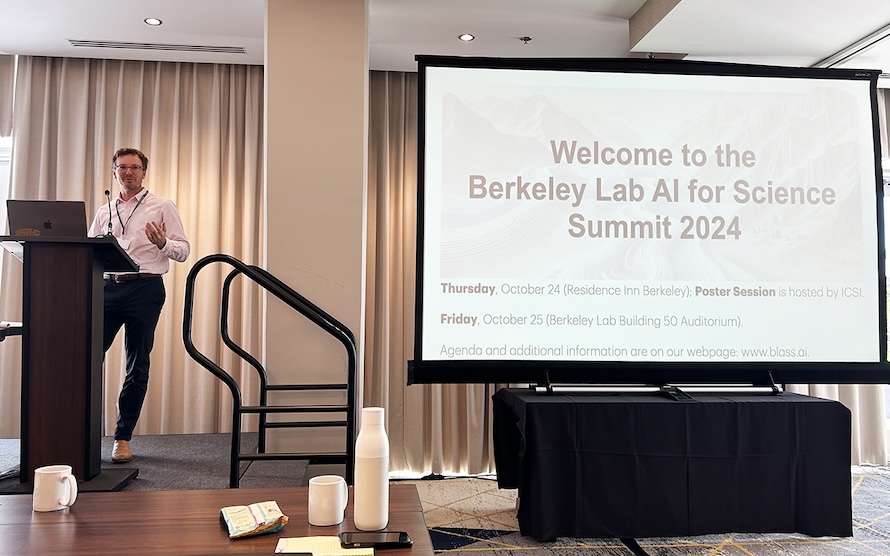 Ben Erichson speaks at a podium to the left of a screen displaying a welcome message.