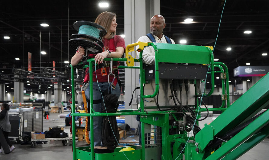 Woman holding a spool of cable and a man on a cherry picker