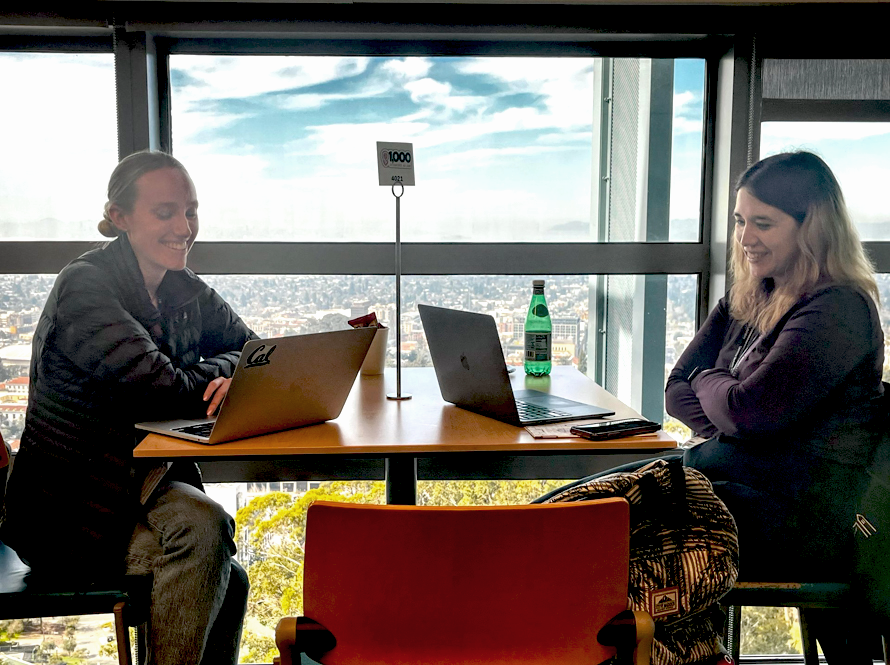 Two scientists with laptops open at a cafe table during the AI Jam.