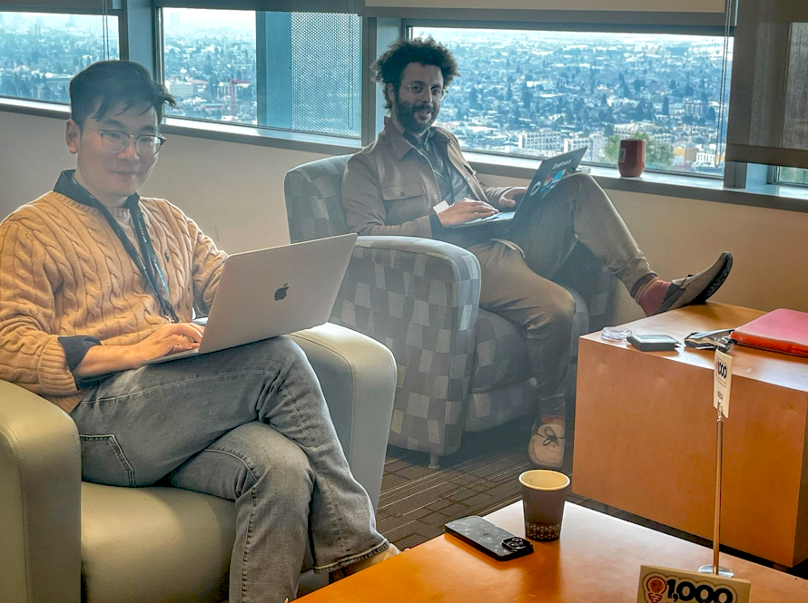 Two scientists compute from easy chairs in a lounge area of Shyh Wang Hall during the AI Jam event.