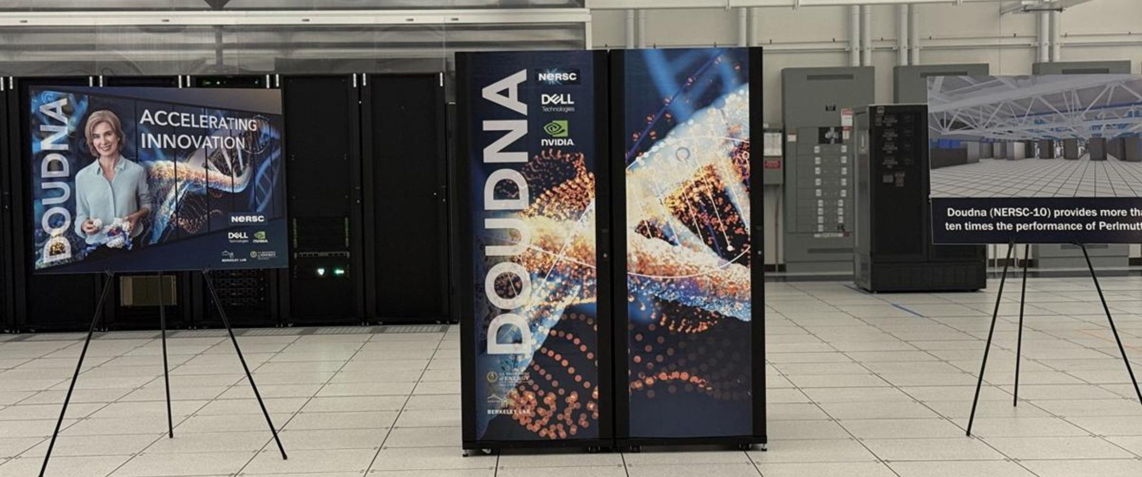 Photo of the Doudna supercomputer at NERSC, featuring display panels with DNA-inspired graphics and information about its advanced performance, including signage noting that Doudna (NERSC-10) provides more than ten times the performance of its predecessor, Perlmutter.